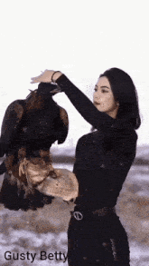 a woman is holding a large bird in her arms and the name gusty betty is on the bottom