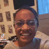 a woman wearing glasses is smiling while sitting on a couch .