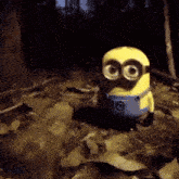 a yellow minion with big eyes is standing on a pile of leaves in the woods .