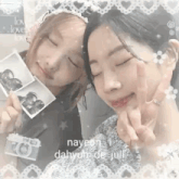 two girls are posing for a picture with their eyes closed and holding a camera .