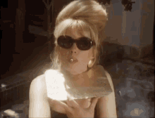 a woman wearing sunglasses is holding a piece of gold in her hand .