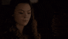 a woman is standing in a dark bedroom with a bed