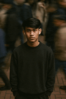 a young man wearing earbuds stands in front of a crowd of people