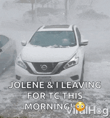 a white nissan suv is driving through a snowy street .