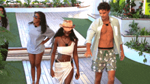 a group of people are walking on a wooden deck and one of them is wearing a straw hat