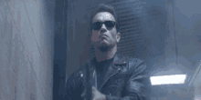 arnold schwarzenegger is holding a gun in a dark room