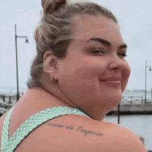 a woman with a tattoo on her shoulder is smiling at the camera .