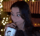 a woman is drinking through a straw from a mug with a picture of a penguin on it .