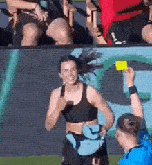 a referee is giving a yellow card to a female athlete on a soccer field .