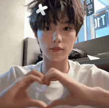 a person with a bandage on their head making a heart shape with their hands