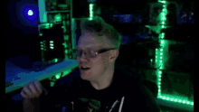 a man wearing glasses is giving the ok sign in a dark room with green lights .
