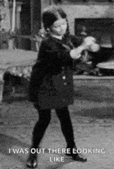 a black and white photo of a little girl dancing in a living room .