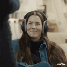 a woman wearing headphones is smiling and looking at the camera