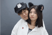 a man wearing a police hat and a woman wearing cat ears are posing for a picture
