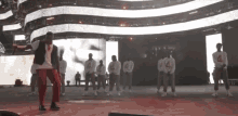 a group of men are dancing in front of a large american flag