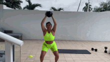 a woman in a neon yellow top and shorts is holding a ball over her head