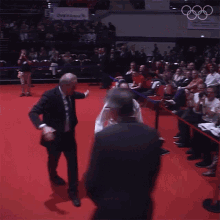 a man in a suit stands behind a woman in a karate uniform