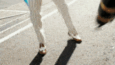 a person wearing white striped pants and brown shoes is walking down the street
