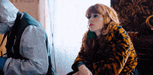a woman in a tiger print coat is sitting in a chair