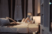 a woman is laying on a bed in a dark room with a rainbow in the background