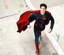 a man in a superman costume is running on a street