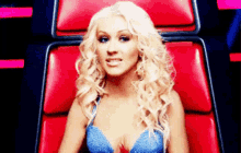 a blonde woman in a blue bra is sitting on a red chair