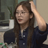 a woman wearing glasses and a blue shirt is holding her head .