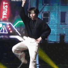a man is dancing in front of a sign that says trust on it