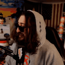 a man with long hair and a beard is wearing sunglasses and a hoodie that says " rage " on it