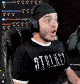 a man wearing headphones is sitting in front of a microphone and making a surprised face .