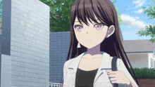 a girl with long dark hair and pink eyes is standing in front of a white brick wall