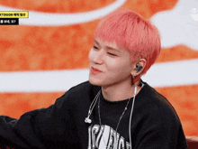 a man with pink hair is wearing ear buds and a black shirt that says nct