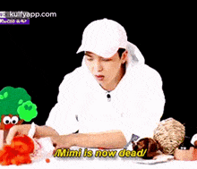 a man in a white hat is sitting at a table with stuffed animals .
