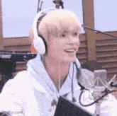 a man wearing headphones is smiling in front of a microphone in a recording studio .