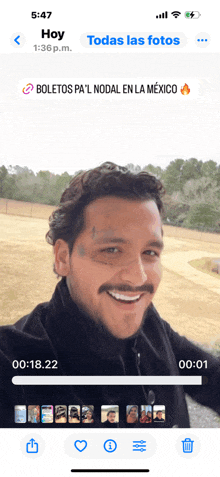 a man with a tattoo on his face is smiling on a cell phone screen