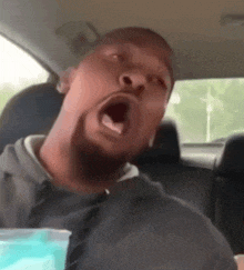 a man is yawning while sitting in a car with his mouth open
