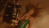 a woman in a green dress is singing into a microphone in front of a drum