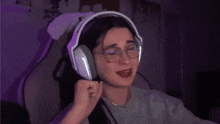 a woman wearing glasses and headphones is smiling and pointing