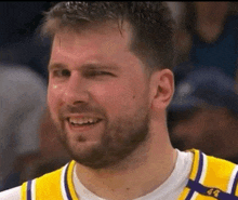 a man with a beard is smiling and wearing a yellow and white jersey with the number 49 on it .