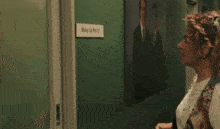 a man and woman are standing in a hallway with a sign that says wake up 8m 01
