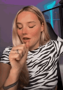 a woman wearing a zebra print shirt is making a gesture with her finger