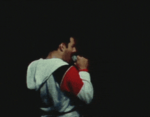 a man singing into a microphone with another man in the background