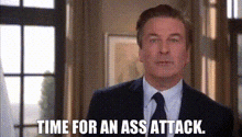 a man in a suit and tie is standing in front of a window and saying `` time for an ass attack . ''