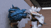 a statue of a blue monster is being attacked by a statue of a white monster