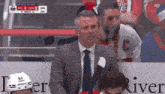 a man in a suit and tie is sitting in the stands watching a hockey game