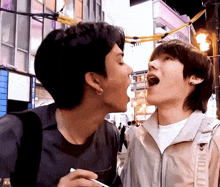 a man wearing a jacket that says vuitton on it kisses another man