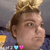 a woman with a bun on her head is making a funny face with a heart in the corner .