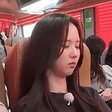 a woman is sitting on a bus with her eyes closed and her hair blowing in the wind .