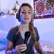 a woman is holding a microphone in front of a tapestry that says " n those and join "