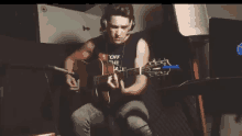 a young man wearing headphones is playing a guitar